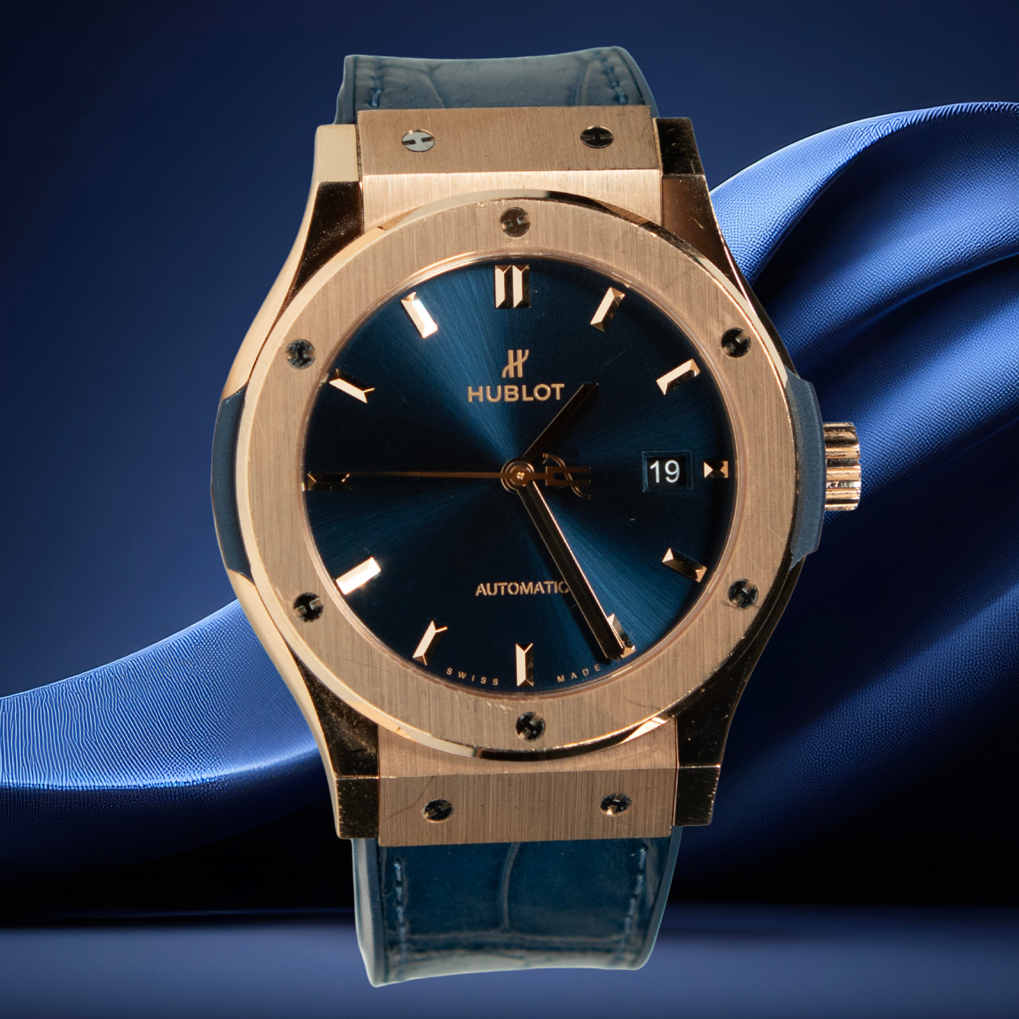 Hublot watch with blue face and rose gold case on a blue fabric background