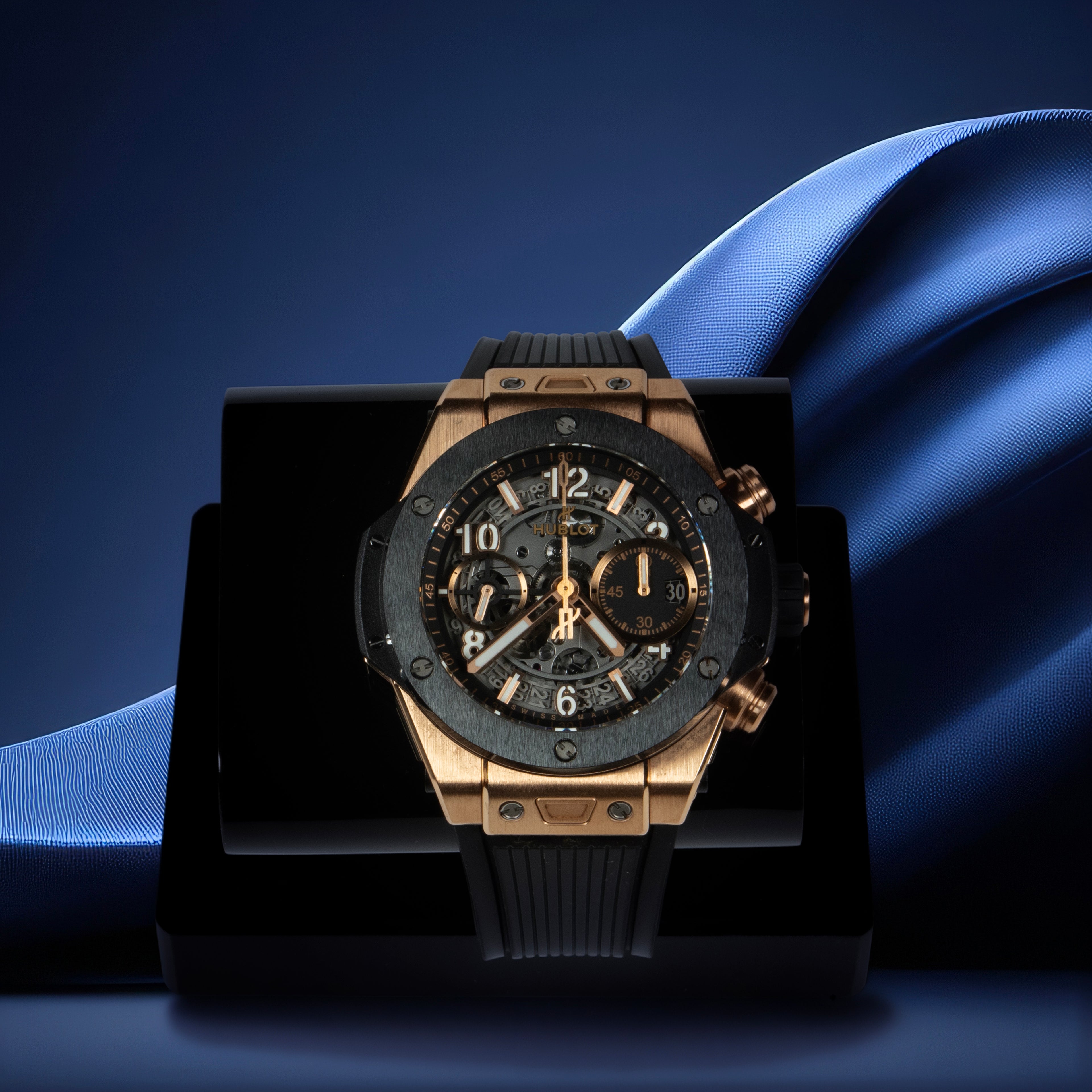 Luxury watch with gold and black design on a blue fabric background