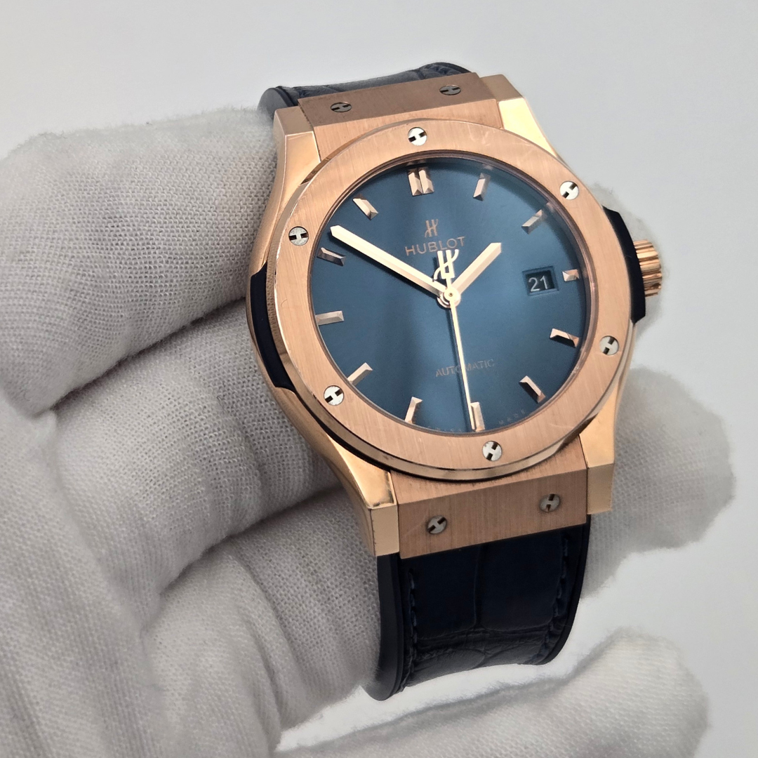 Luxury watch with rose gold case and blue dial on a gray background