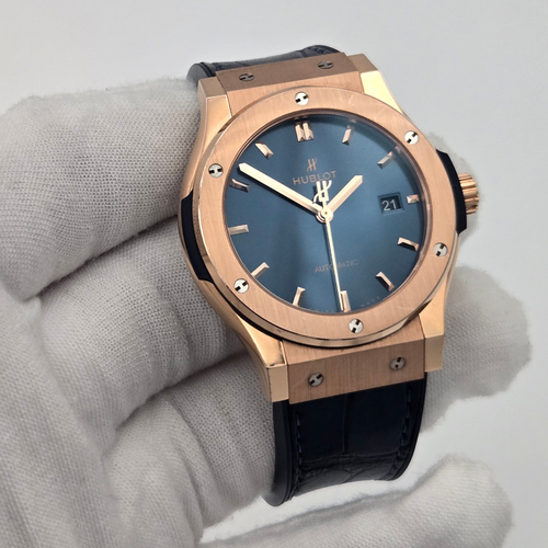 Luxury watch with rose gold case and blue dial on a gray background