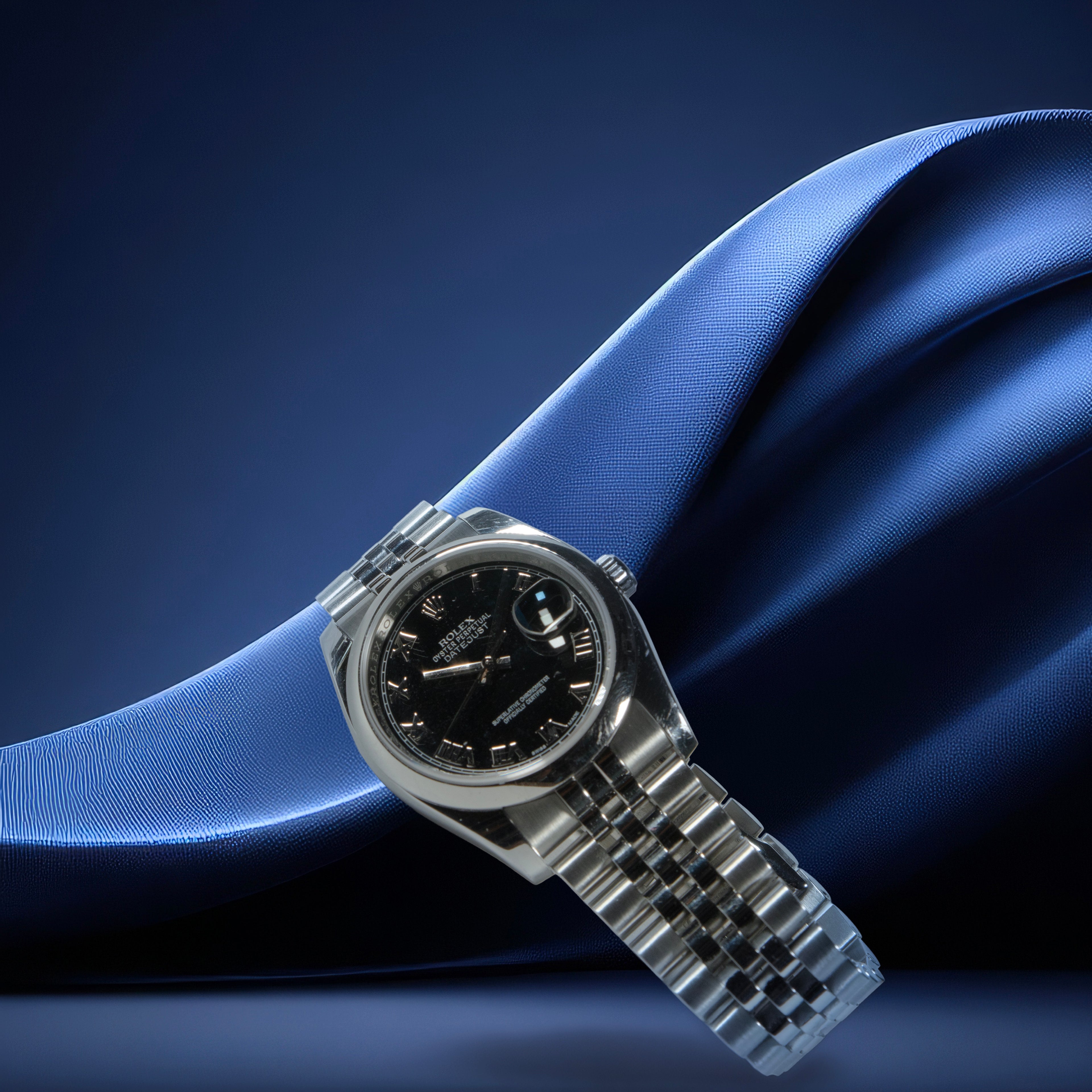 Rolex Datejust 36 watch with a black face on a blue fabric background
