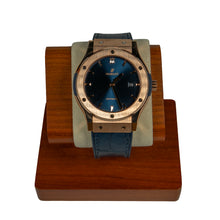Hublot watch with blue face and leather strap on a wooden stand